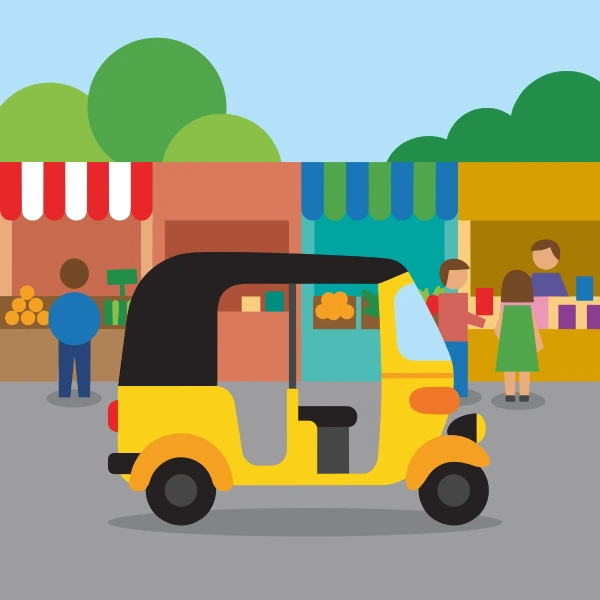 Coral, black, and teal auto rickshaw in front of colorful buildings, storefronts, signs, and clean pavement.